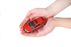 Image of a small red toy car held in the palm of two hands.